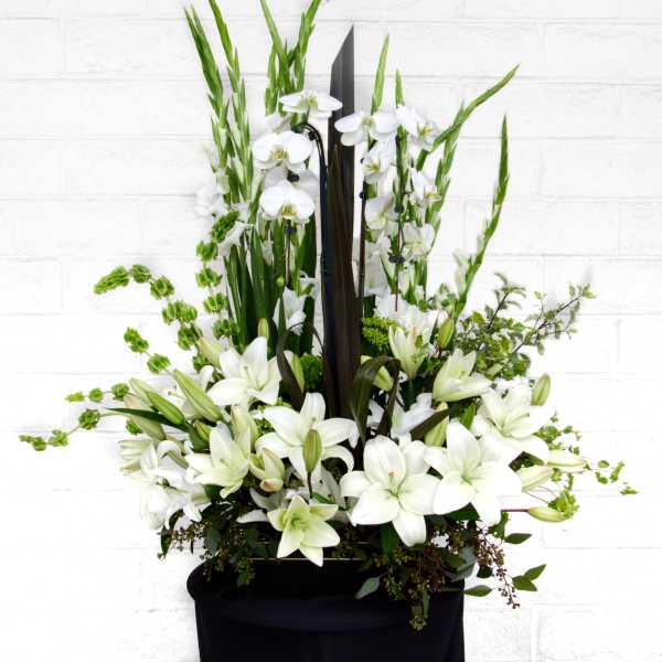 White lilies and orchids arranged in a tall black container