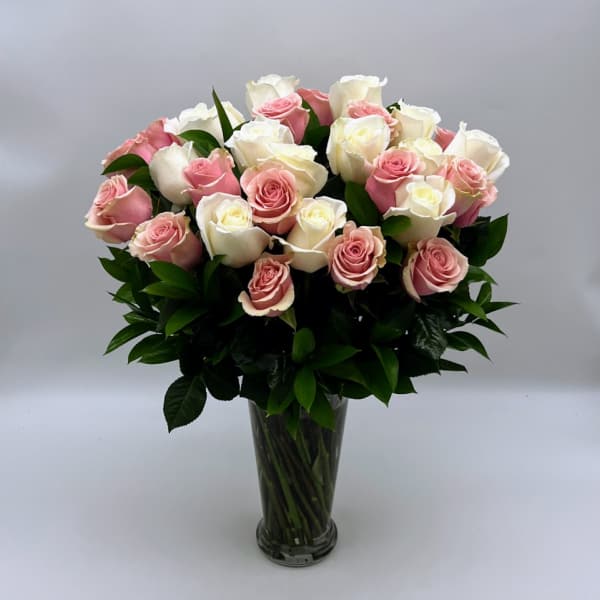 Pink and white roses arranged in a clear glass vase
