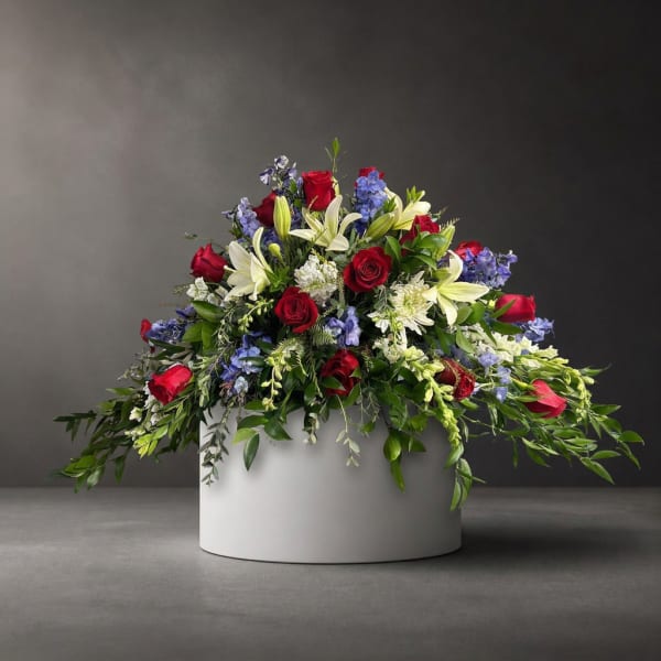 Red roses and white lilies arranged in a white round container