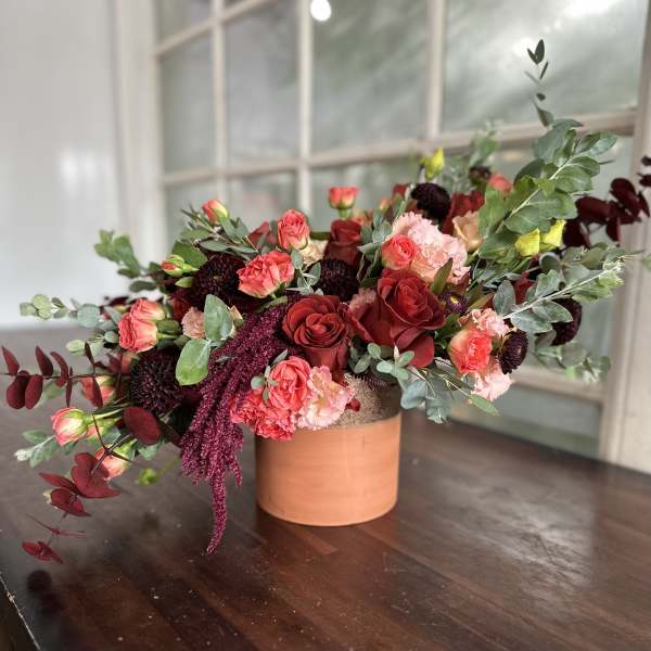 Red and pink rose arrangement in a terracotta vase