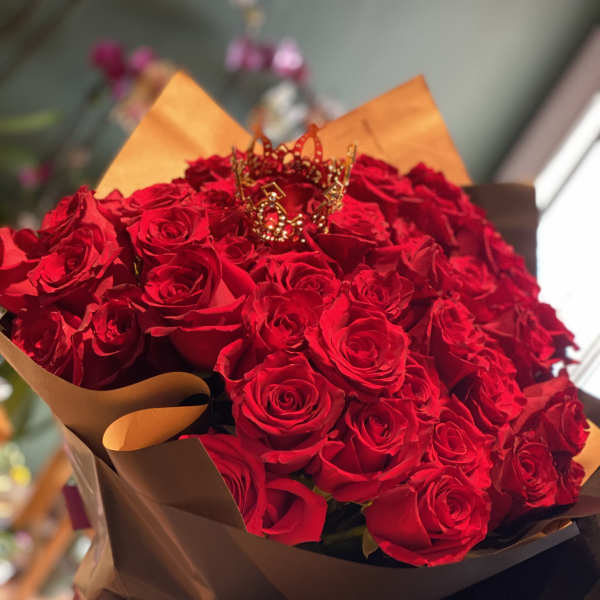 Bouquet of red roses wrapped in brown paper with a decorative crown