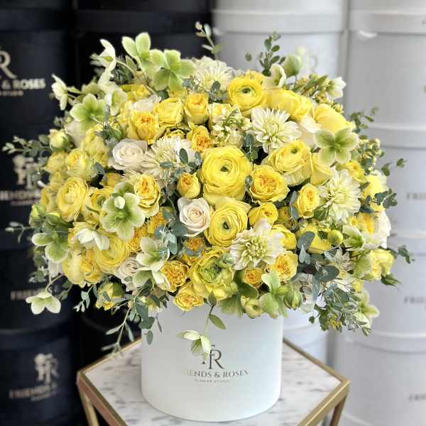 Yellow and white flower arrangement in a white hat box