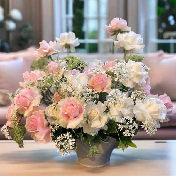Pink and white roses arranged in a gray vase