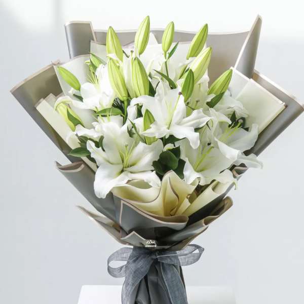 Bouquet of white lilies wrapped in gray paper with a ribbon