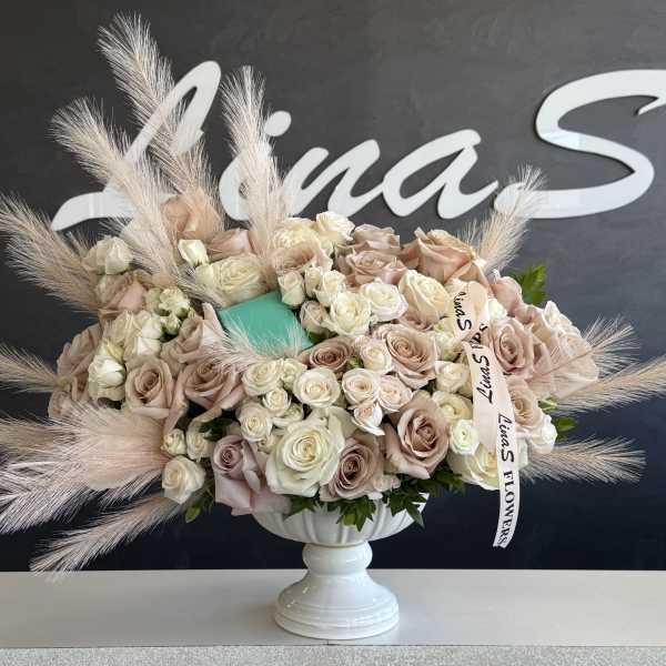 Large bouquet of blush and ivory roses in a white pedestal vase