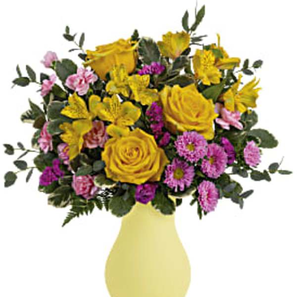 Yellow roses and pink flowers in a pale yellow vase