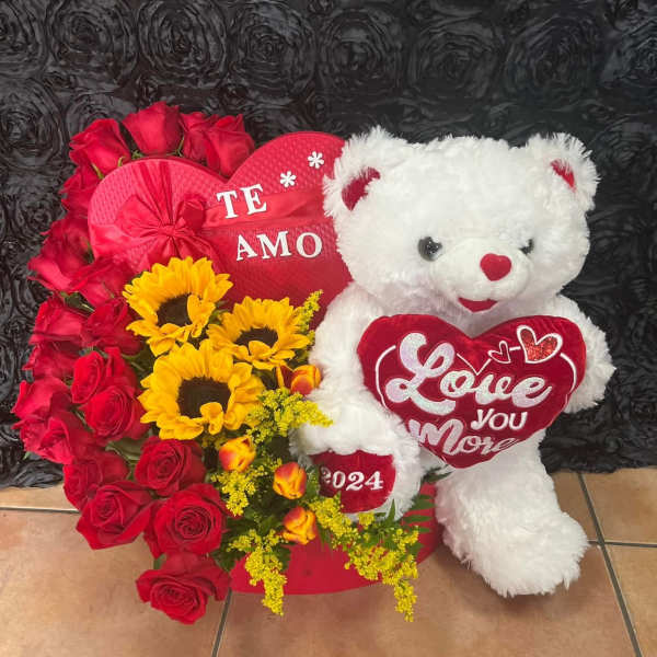 Red roses and sunflowers arranged with a white teddy bear and heart decorations