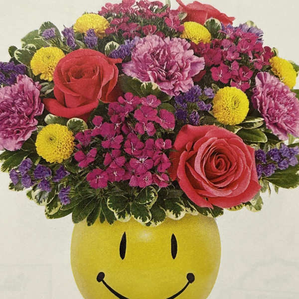 Mixed flower arrangement in a yellow smiley-face container