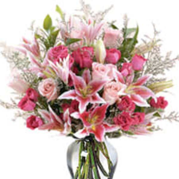 Pink lilies and roses arranged in a clear glass vase