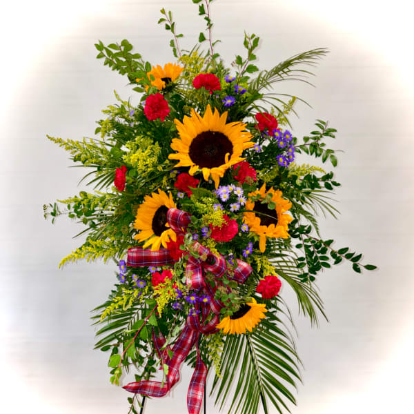 Tall floral spray with sunflowers, red carnations, purple daisies, and plaid ribbon