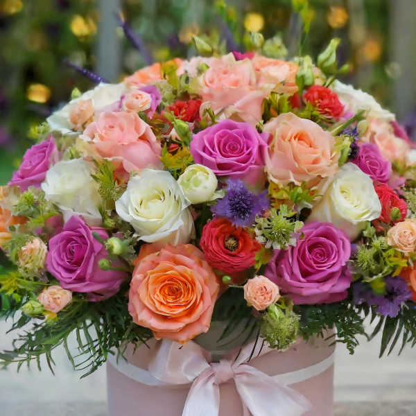 Mixed roses in a pink hat box with a satin ribbon