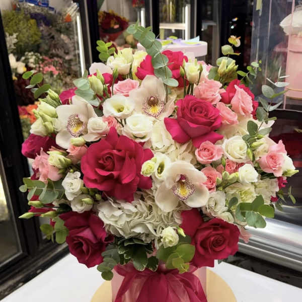 Bouquet of pink and white roses with white orchids in a pink box