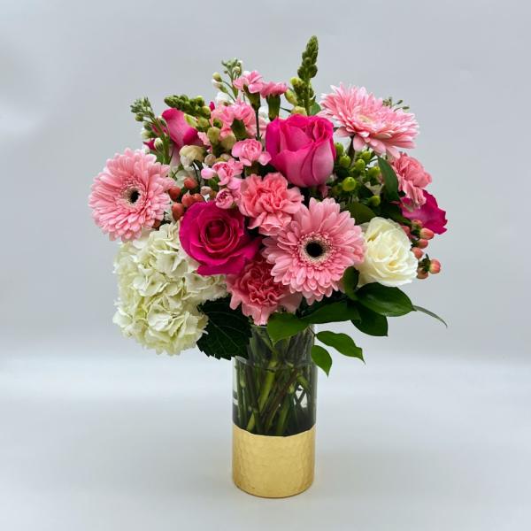 Pink and white mixed bouquet in a clear glass vase with a gold wrap