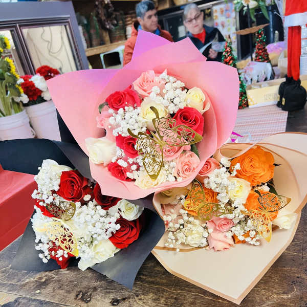 Three rose bouquets wrapped in pink, black, and beige paper