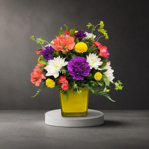 Colorful mixed flower arrangement in a yellow glass vase