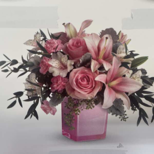 Pink roses and lilies arranged in a pink glass vase