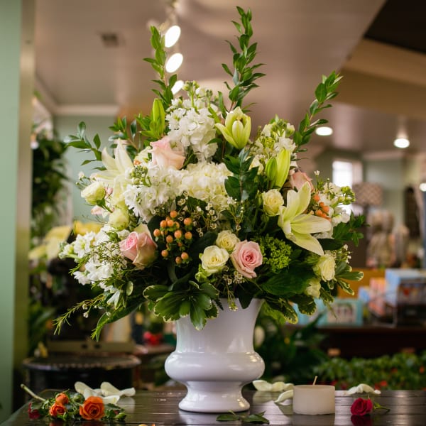 Large white vase arrangement with white lilies, roses, and pink accents