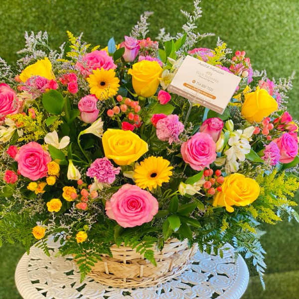 Basket arrangement of pink and yellow roses with mixed flowers