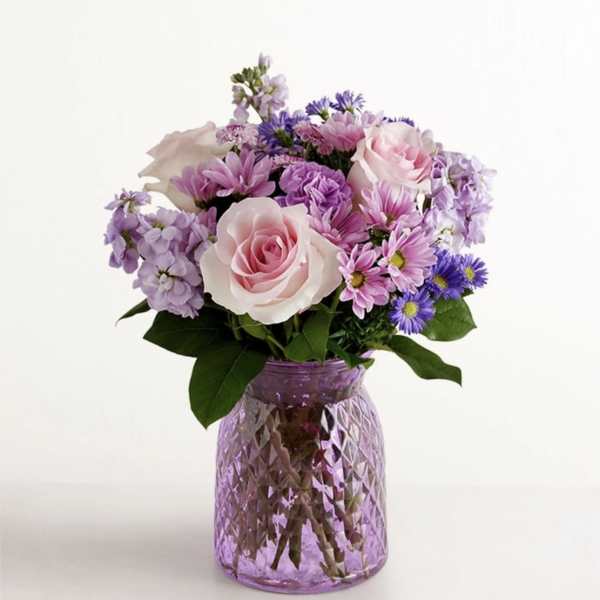 Pink and lavender mixed bouquet in a purple glass vase