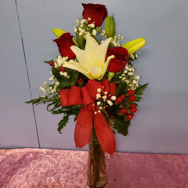 Bouquet of red roses and white lilies in a glass vase with a red ribbon