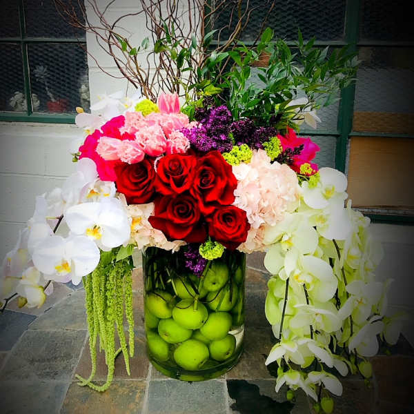 Large floral arrangement with red roses and white orchids in a glass vase