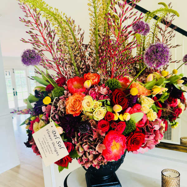 Large mixed floral arrangement in a black vase with tall stems