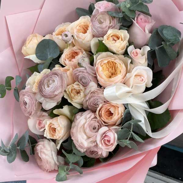 Bouquet of blush and peach roses with eucalyptus wrapped in pink paper