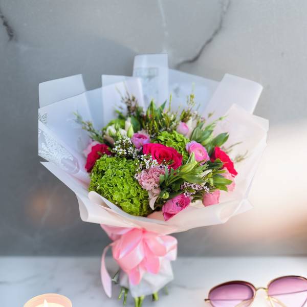 Bouquet of pink roses and green hydrangea wrapped in white paper