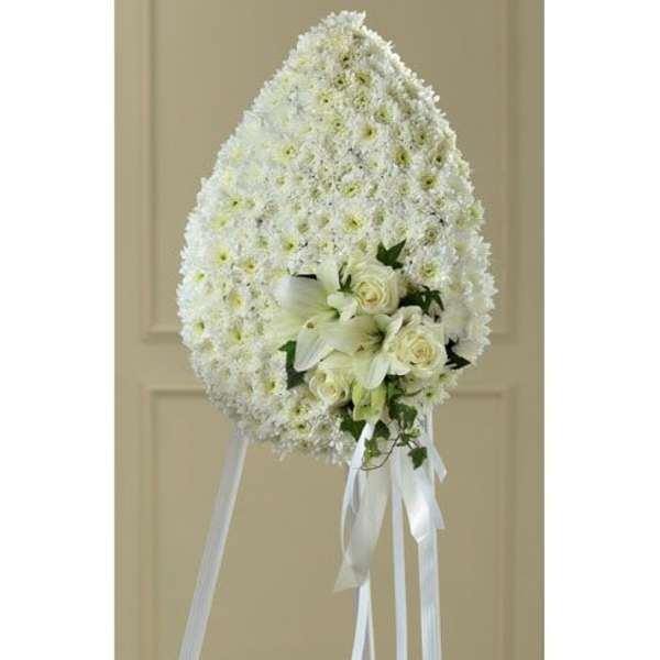 White standing floral spray with roses and lilies on a ribboned easel