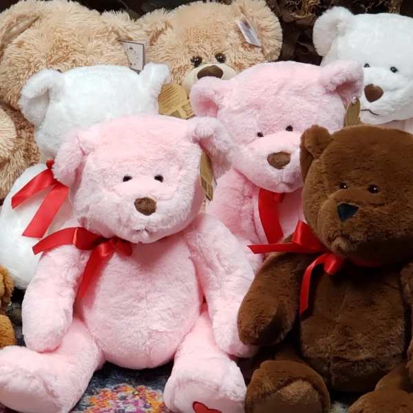 Plush teddy bears in pink, white, tan, and brown with red ribbons