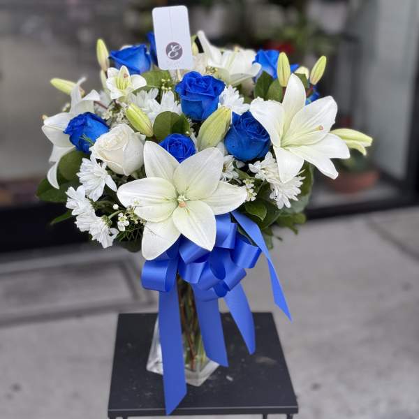 Blue and white bouquet with lilies and roses in a glass vase