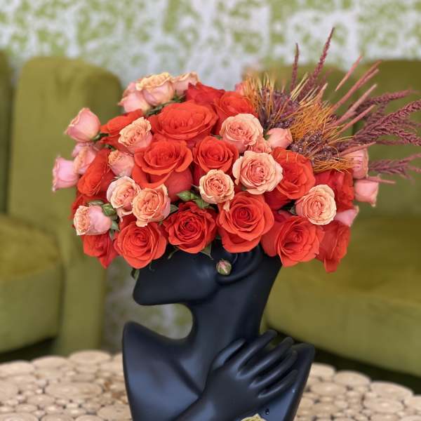 Red and peach roses arranged in a black sculptural vase