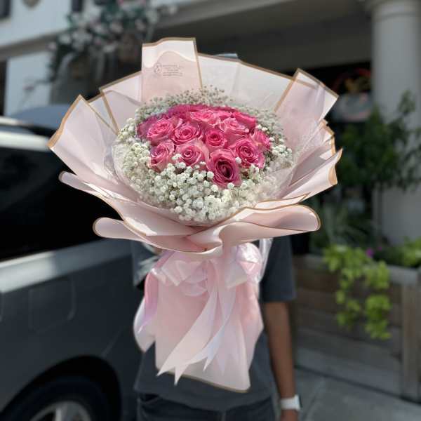 Pink rose bouquet wrapped in pale pink paper with white filler flowers