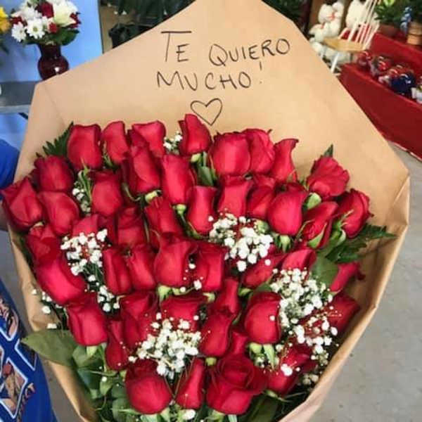 Bouquet of red roses wrapped in tan paper with a handwritten note