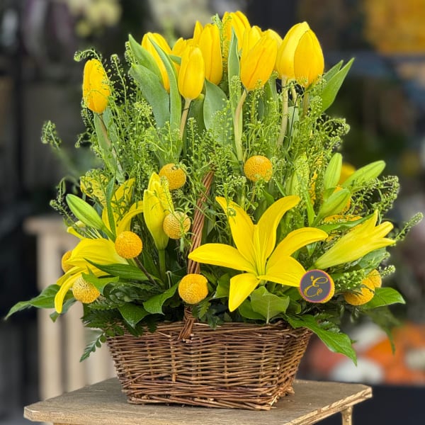 Yellow tulips and lilies arranged in a wicker basket