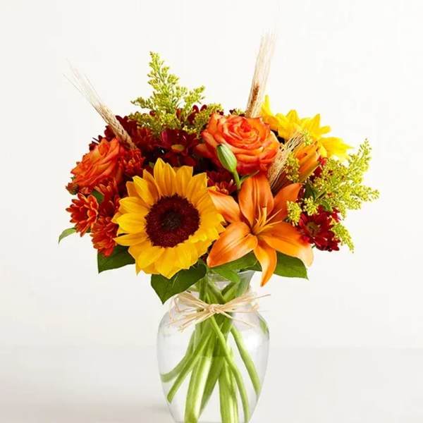 Sunflower and orange lily bouquet in a clear glass vase