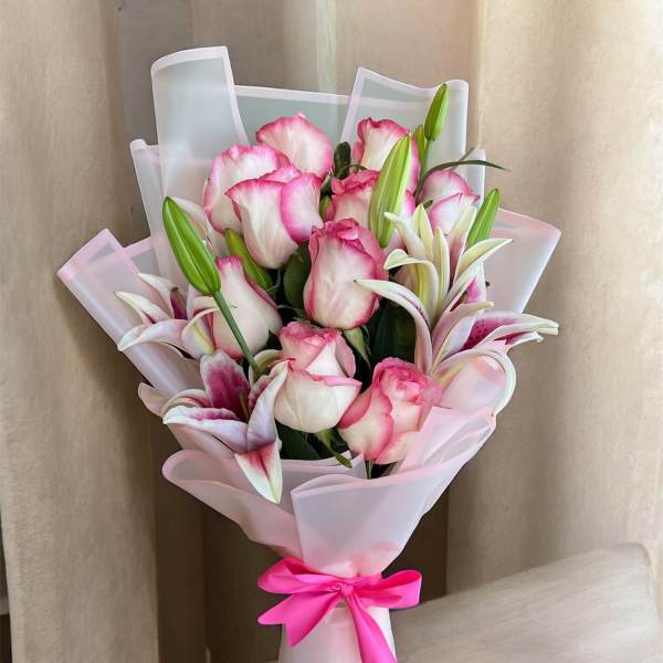 Pink and white rose bouquet with lilies wrapped in pale pink paper
