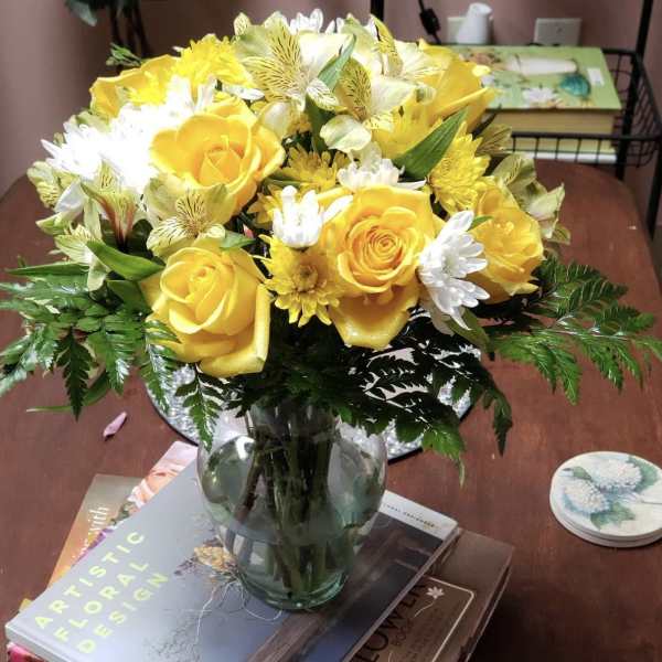 Yellow roses and white daisies arranged in a glass vase