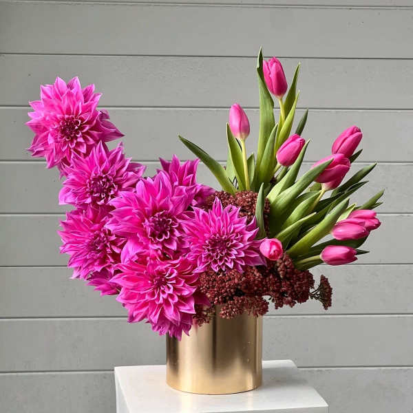 Pink dahlias and tulips arranged in a gold vase
