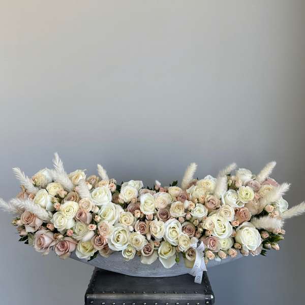 Low arrangement of cream and blush roses in a gray container