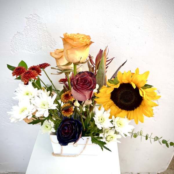 Mixed bouquet with sunflowers, roses, and white daisies in a white box