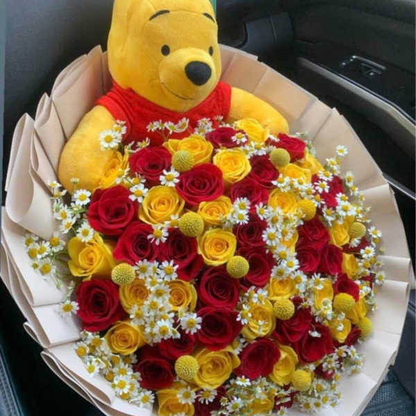 Bouquet of red and yellow roses with a Winnie the Pooh plush