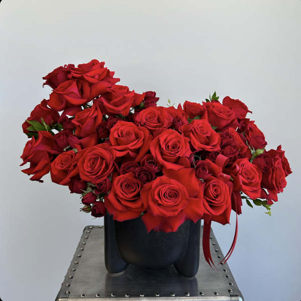 Red rose arrangement in a black vase