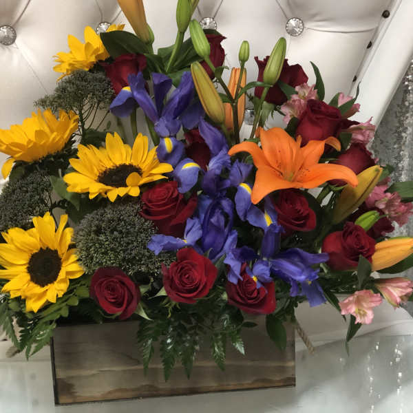 Mixed bouquet with sunflowers, roses, lilies, and irises in a wooden box