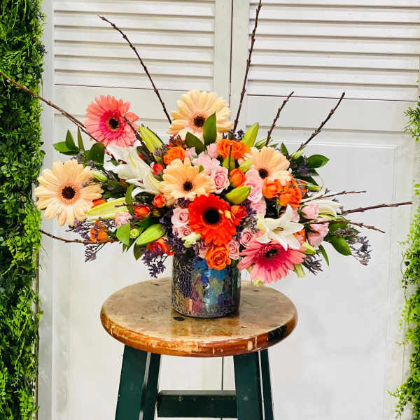 Colorful mixed bouquet in a patterned vase with gerbera daisies and roses