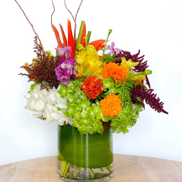 Colorful mixed flower arrangement in a green glass vase