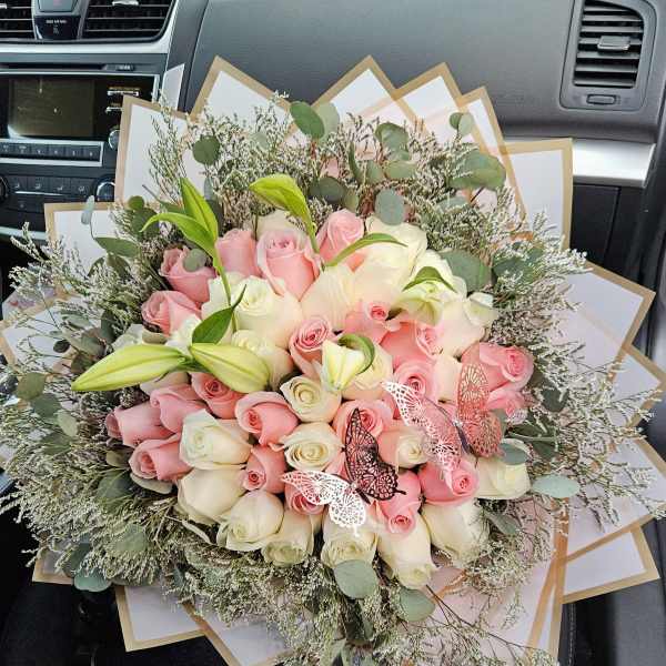 Bouquet of pink and white roses with lilies and butterfly accents