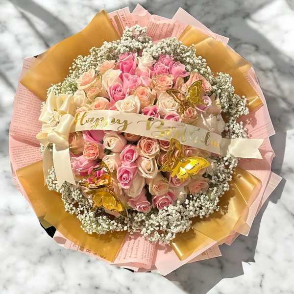 Bouquet of pink and cream roses with a birthday ribbon and butterfly accents