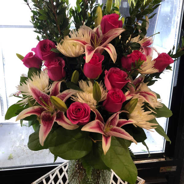 Pink roses and lilies arranged in a clear glass vase