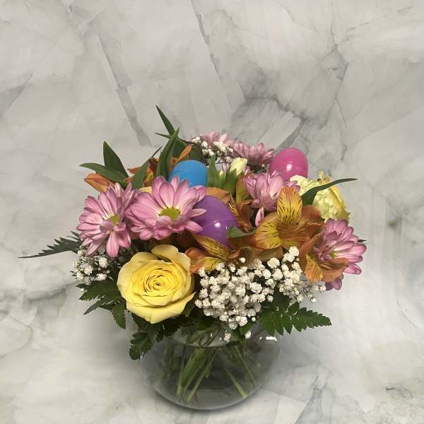 Mixed bouquet of pink daisies, yellow rose, and alstroemeria in a glass vase